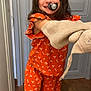 Ohana participe au concours pour gagner de l'argent avec cette photo : child, girl, pajamas, orange_clothing, floral_pattern, pacifier, mittens, indoor, wooden_floor, door, smiling, long_hair, cute, standing, playful, happy, person, footwear, cartoon_character, cozy