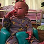 Maliki is registered to the contest to win money with this photo: baby, child, infant, onesie, sitting, teal_seat, finger_near_mouth, curious_expression, living_room, pink_couch, flowers, vase, carpet, indoors, cute, cozy, young_child, plush_toys, home, casual_clothing