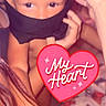 child, face, eyes, hand, black_cloth, heart_sticker, baby_bottle, arm, skin, indoors, person, cute, playful, closeup, young_child, expression, baby, covering_face, affection, warm_lighting
