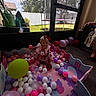 Haislyn joined the competition — help win amazing prizes! child, toddler, ball_pit, balloons, pink_dress, bow, indoor, play, toy, foam_mat, window, backyard, grass, tree, sunlight, person, floor, happy, smile, colorful