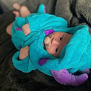 Rosie joined the competition — help win amazing prizes! baby, infant, pacifier, costume, turquoise, purple, plush, blanket, soft, cute, lying_down, face, child, indoors, portrait, cozy, sleepwear, headwear, expression, young