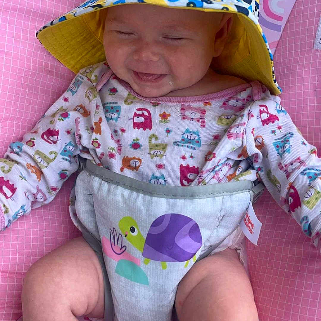 Isabella joined the competition — help win amazing prizes! baby, babylaughing, bonnet, cap, clothing, coat, cushion, diaper, face, happy, hat, head, homedecor, person, photography, portrait, sitting, smile, sunhat, tape