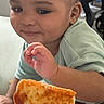 toddler, child, grilled_cheese, food, hand, smile, indoor, curious, face, person, clothing, plate, light, table, closeup, expression, skin, sitting, young_child, meal