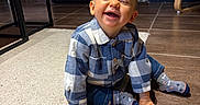 Noah participe au concours pour gagner de l'argent avec cette photo : baby, carpet, checkered_shirt, cheerful, child, cute, floor_tiles, furniture, hand, happy, home_interior, indoor, living_room, playful, portrait, sitting, smiling, socks, toddler, wooden_chair