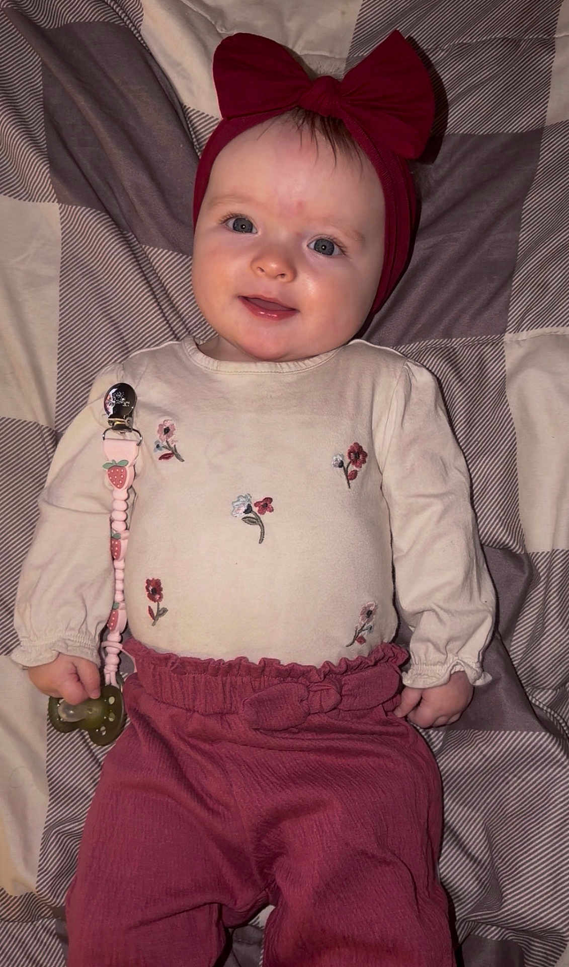 Delilah joined the competition — help win amazing prizes! baby, infant, headband, bow, pacifier, clothing, blanket, pattern, smile, face, child, cute, lying_down, pink, maroon, hand, eyes, rosy_cheeks, happy, indoors