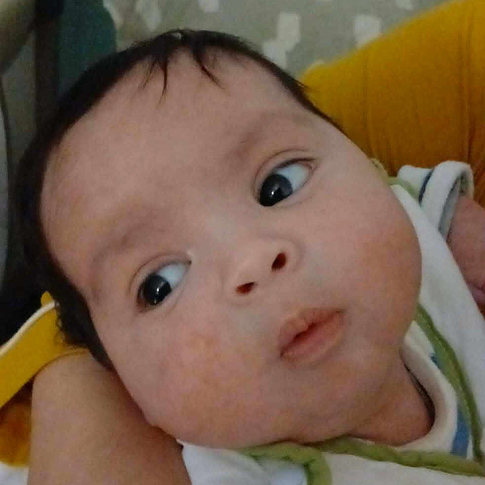 Jawed Daniel participe au concours pour gagner de l'argent avec cette photo : arm, baby, child, close_up, clothing, curious, expression, eyes, face, hand, head, holding, indoor, infant, person, pillow, skin, striped_clothing, yellow_sleeve, young