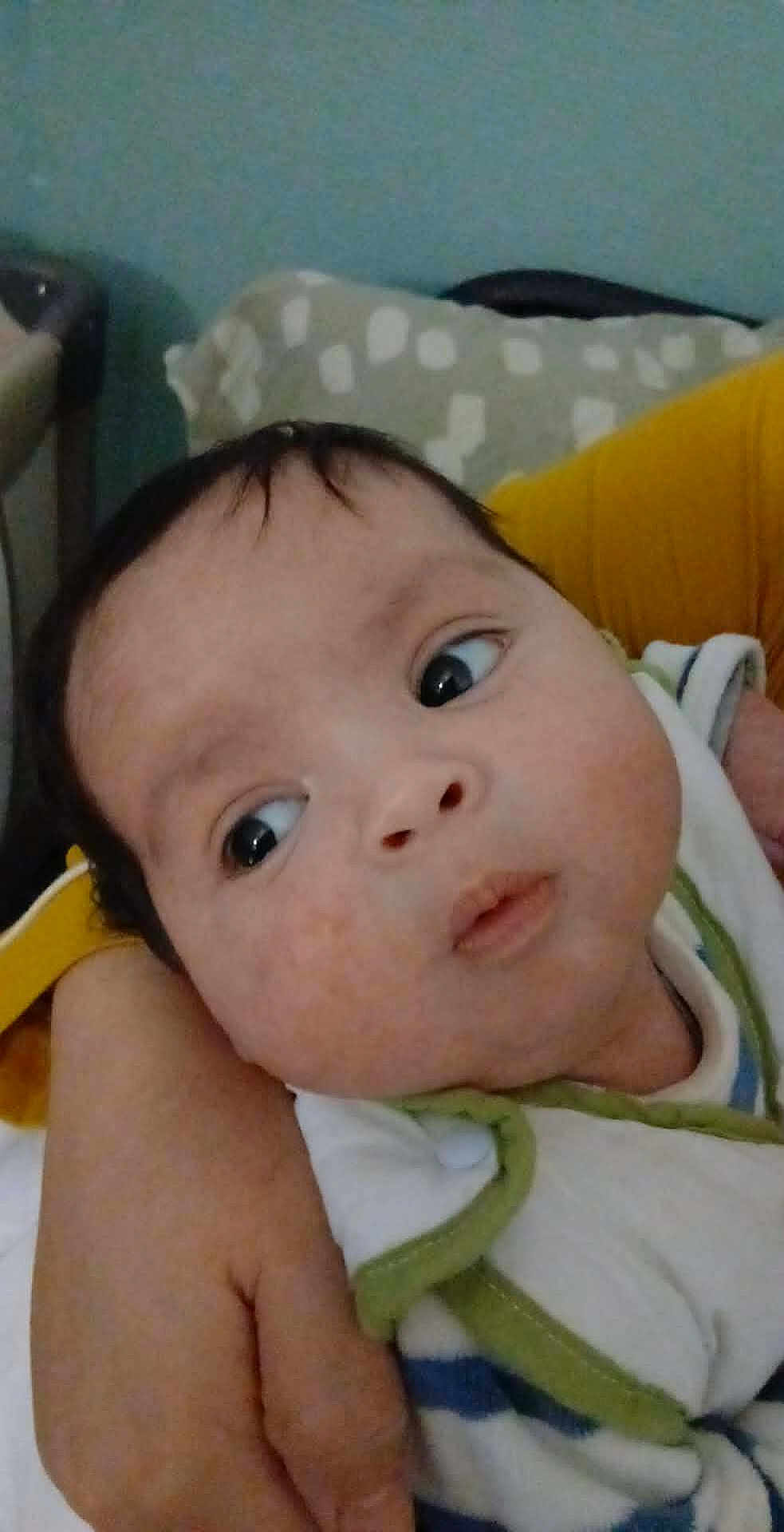 Jawed Daniel participe au concours pour gagner de l'argent avec cette photo : baby, infant, face, eyes, hand, clothing, striped_clothing, pillow, arm, yellow_sleeve, indoor, person, skin, head, curious, expression, close_up, holding, child, young
