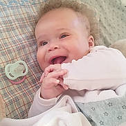 Athena participe au concours pour gagner de l'argent avec cette photo : baby, bed, blanket, child, clothing, comfort, cozy, cute, expression, face, hands, happy, indoor, infant, lying_down, pacifier, plush_toy, portrait, smiling, soft
