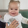Athena participe au concours pour gagner de l'argent avec cette photo : baby, bib, child, clothing, couch, curly_hair, cute, face, hand, happy, holding, home, indoor, infant, person, pillow, portrait, sitting, smile, young_child