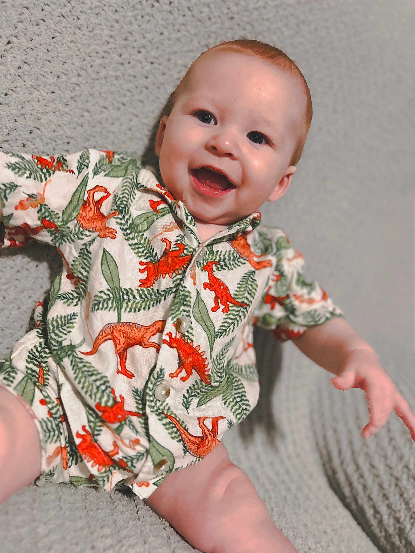 Elijah joined the competition — help win amazing prizes! baby, smiling, dinosaur_print, shirt, infant, happy, cute, child, portrait, texture, blanket, clothing, sitting, face, young, fun, pattern, relaxed, indoors, person