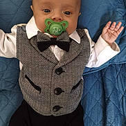 Luka participe au concours pour gagner de l'argent avec cette photo : baby, pacifier, vest, bow_tie, white_shirt, black_pants, blue_blanket, quilted_blanket, infant, lying_down, cute, face, hand, clothing, portrait, indoors, baby_fashion, child, person, newborn
