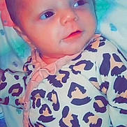 Taylor is registered to the contest to win money with this photo: baby, infant, leopard_print, onesie, face, eyes, blanket, cute, child, newborn, lying_down, soft_toys, patterned_clothing, portrait, skin, head, expression, young, indoors, resting