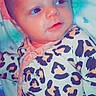 baby, infant, leopard_print, onesie, face, eyes, blanket, cute, child, newborn, lying_down, soft_toys, patterned_clothing, portrait, skin, head, expression, young, indoors, resting