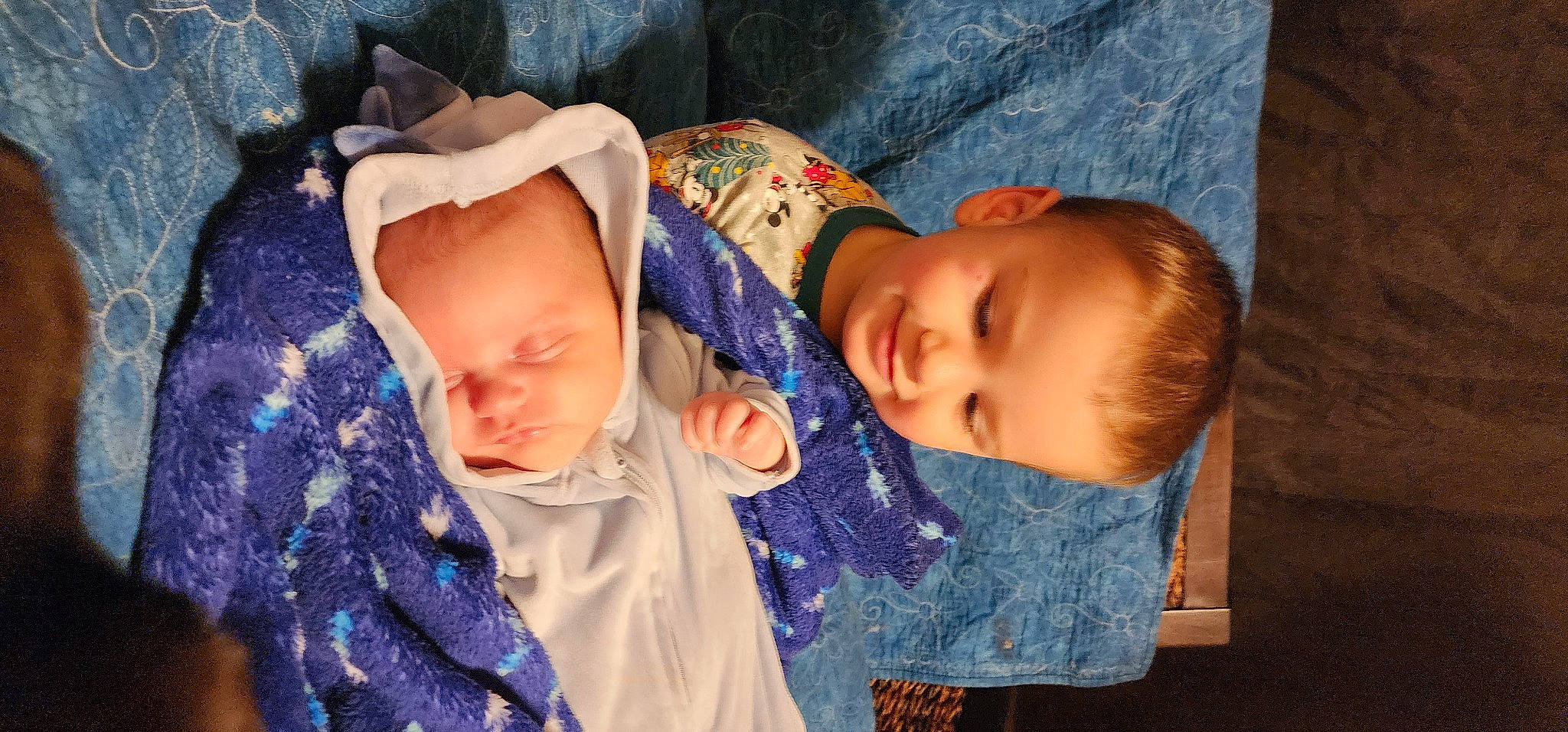 Lucca is registered to the contest to win money with this photo: baby, baby_products, baby_toddler_clothing, cheek, child, comfort, electric_blue, eye, fun, happy, iris, joy, pattern, person, sitting, skin, sleeve, textile, toddler, wood