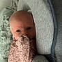 Oaklee is registered to the contest to win money with this photo: baby, infant, face, onesie, floral_pattern, cushion, gray, bed, blanket, hand, sleepwear, person, newborn, indoors, comfort, soft, cute, curious, resting, closeup