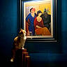 cat, painting, artwork, blue_wall, wooden_stairs, indoor, lighting, abstract_art, colorful, curious_cat, portrait_painting, framed_art, decor, furniture, animal, pet, sitting, light_source, shadow, warm_light