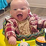 baby, child, smiling, plaid_shirt, baby_walker, toy, elephant_plush, indoor, happy, infant, clothing, playtime, colorful, mouth_open, cheerful, person, cute, head, face, young