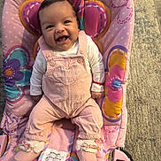 Amiri Lopez joined the competition — help win amazing prizes! baby, infant, child, smiling, happy, portrait, seated, indoor, pink, clothing, overalls, booties, baby_seat, cushion, colorful, playful, face, floor, furniture, photography