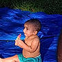 baby, child, boy, popsicle, blue_tarp, sitting, wet_skin, shorts, grass, outdoor, night, summer, food, snack, bare_chest, cute, portrait, focus, playtime, fun