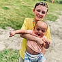 Colby is registered to the contest to win money with this photo: child, baby, smiling, yellow_shirt, plaid_shorts, outdoor, grass, happy, holding, person, sibling, cute, summer, footwear, shorts, playing, nature, portrait, sunny_day, family