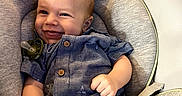 Gunner joined the competition — help win amazing prizes! baby, smiling, car_seat, blue_shirt, beige_shorts, happy, child, infant, clothing, seat_belt, indoor, person, cute, furniture, sitting, portrait, young_child, baby_toy, pacifier, comfort