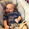 baby, smiling, car_seat, blue_shirt, beige_shorts, happy, child, infant, clothing, seat_belt, indoor, person, cute, furniture, sitting, portrait, young_child, baby_toy, pacifier, comfort