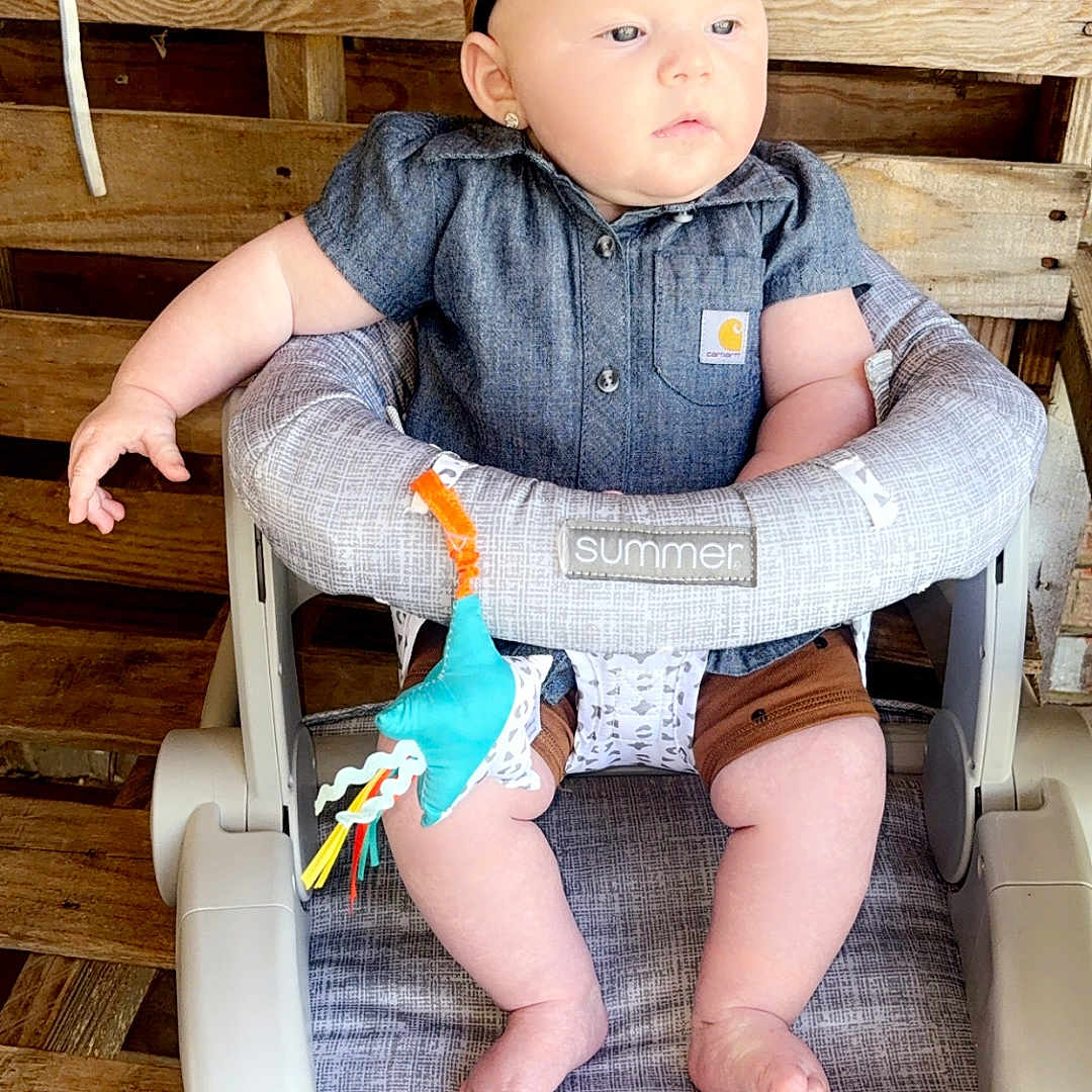 Brooklen is registered to the contest to win money with this photo: baby, baby_seat, bow, casual_clothing, child, closeup, curious, cushion, cute, denim_shirt, earrings, feet, headband, indoor, infant, pale_skin, sitting, small_toy, toy, wooden_background