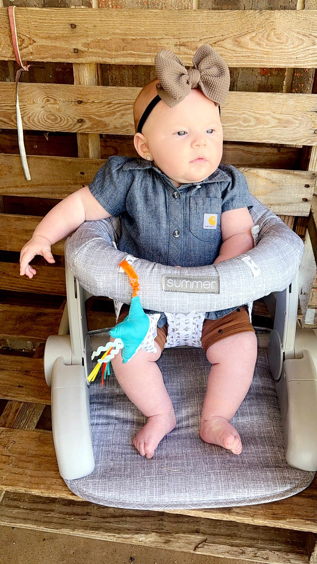 Brooklen is registered to the contest to win money with this photo: baby, baby_seat, bow, casual_clothing, child, closeup, curious, cushion, cute, denim_shirt, earrings, feet, headband, indoor, infant, pale_skin, sitting, small_toy, toy, wooden_background