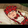 baby, infant, plaid, hat, bow_tie, red, white_clothing, blanket, cozy, smiling, face, portrait, cute, indoors, floor, wood, child, person, holiday, festive