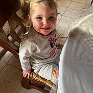 Lyna participe au concours pour gagner de l'argent avec cette photo : child, smiling, indoor, wooden_chair, table, plastic_cover, tiled_floor, sweatshirt, minnie_mouse, pigtails, happy, person, cute, portrait, girl, casual_clothing, light, face, seated, young