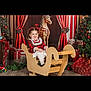 Lyna a rejoint le concours — aidez-le/la à gagner de superbes lots ! child, girl, rocking_horse, wooden_toy, christmas_tree, presents, holiday_decor, red_curtains, plaid_dress, smiling, festive, indoor, flooring, wreath, ornaments, ribbons, christmas_lights, holiday, decorations, portrait