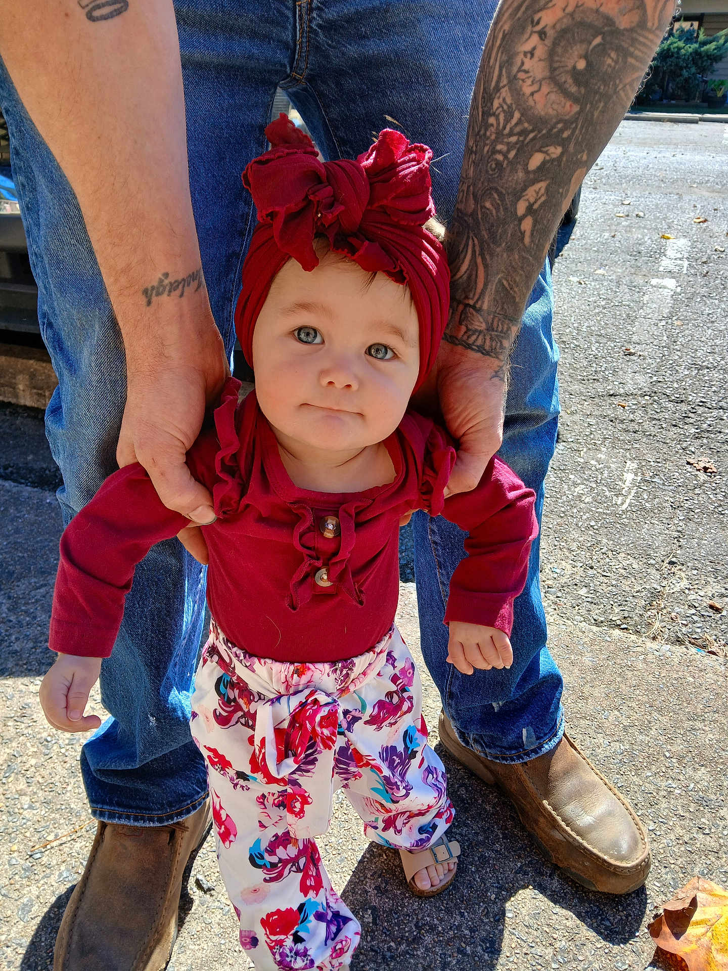 Hileigh joined the competition — help win amazing prizes! toddler, child, adult, hands, tattoo, red_headwrap, red_top, floral_pants, sandals, jeans, boots, outdoor, sidewalk, sunlight, person, portrait, cute, support, standing, casual