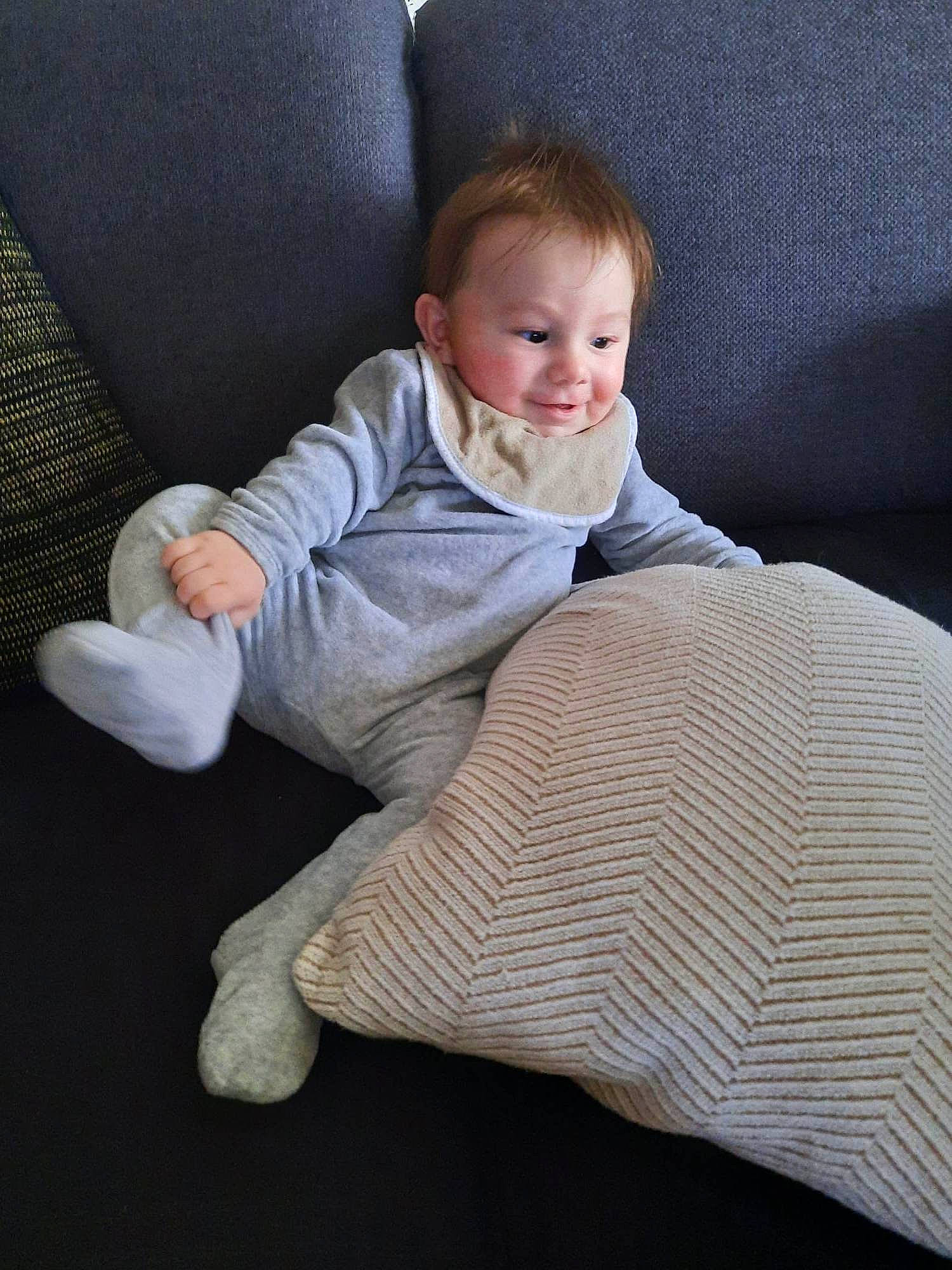 Lyron participe au concours pour gagner de l'argent avec cette photo : baby_toddler_clothing, chair, comfort, couch, finger, floor, flooring, foot, grass, human_leg, leg, linens, person, skin, sleeve, smile, sock, textile, toddler, wood