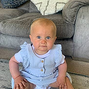 Ember is registered to the contest to win money with this photo: baby, child, infant, sitting, blue_eyes, dress, lace, hands, carpet, couch, pillows, indoor, furniture, cute, young_child, person, portrait, home, floor, serious_expression