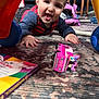 Cy joined the competition — help win amazing prizes! baby, crawling, carpet, toy_car, colorful, indoor, child, playtime, hands, face, smiling, plastic, furniture, book, floor, person, clothing, head, happy, room