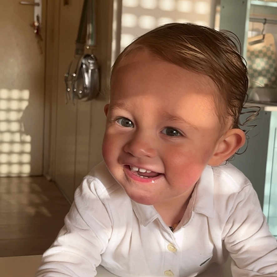 Noah participe au concours pour gagner de l'argent avec cette photo : toddler, child, smiling, white_shirt, crayon, table, indoor, door, shadow, sunlight, hair, face, hand, candid, happy, boy, room, cabinet, furniture, portrait