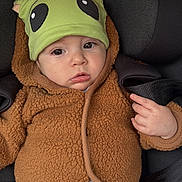 Ethan a rejoint le concours — aidez-le/la à gagner de superbes lots ! baby, child, car_seat, hat, green_hat, brown_jacket, clothing, cute, infant, face, portrait, child_seat, seatbelt, warm_clothing, expression, indoor, person, small_child, headwear, casual