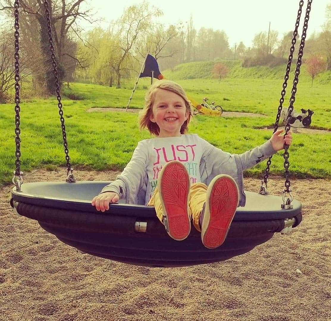 Maëlys participe au concours pour gagner de l'argent avec cette photo : child, fun, grass, happy, joy, leisure, outdoor_play_equipment, person, plant, play, playground, public_space, recreation, sitting, sky, smile, swing, toddler, tree