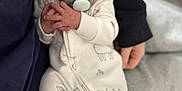 Nathan is registered to the contest to win money with this photo: baby, infant, pacifier, onesie, sheep_pattern, hand, face, clothing, adult_hand, sitting, cozy, soft_lighting, bed, blanket, person, newborn, cute, portrait, indoor, resting