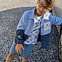 accessories, boy, car, casual_clothing, child, daylight, fashion, gate, glasses, gravel, happy, jacket, outdoor, person, playful, shorts, smiling, sneakers, standing, sunlight