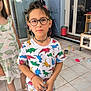 boy, bracelet, casual_clothing, child, dinosaur_tshirt, door, dress, floor, footwear, furniture, girl, glasses, home, indoor, necklace, play, shorts, tile_floor, toy, window