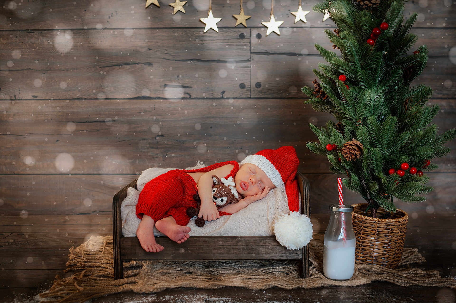 Kade joined the competition — help win amazing prizes! newborn, baby, sleeping, santa_hat, red_clothing, plush_toy, wooden_bed, blanket, christmas_tree, pine_cones, red_berries, milk_bottle, striped_straw, wooden_background, golden_stars, rug, holiday_theme, festive, indoors, cozy