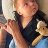 baby, child, infant, portrait, sitting, looking_up, wide_eyes, black_outfit, plush_toy, reindeer, stuffed_animal, cushioned_seat, adult, hand, arm, tattoo, car_seat, indoor, close_up, family