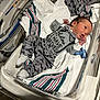 newborn, baby, hospital_bassinet, blanket, clothing, pacifier, infant, person, cute, lying_down, footwear, bed, striped_blanket, socks, hospital, cute_outfit, mustache_print, alert, small_hands, indoors