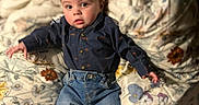 Damon is registered to the contest to win money with this photo: baby, barefoot, bed, blanket, casual_wear, child, clothing, curious, cute, expression, face, floral_pattern, indoors, jeans, person, portrait, shirt, skin, toddler, young_child
