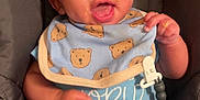 Kane joined the competition — help win amazing prizes! baby, child, car_seat, bib, food, face, expression, clothing, blue, teddy_bear, sitting, indoors, cute, smile, happy, infant, person, small_hands, footwear, sock