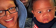 Bleu is registered to the contest to win money with this photo: woman, man, baby, glasses, hoodie, denim_jacket, cap, smile, serious_expression, outdoor, night, family, portrait, face, people, child, casual_clothing, flag_patch, closeup, group