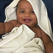 Bleu is registered to the contest to win money with this photo: baby, smiling, towel, hooded_towel, teeth, arm, skin, blanket, happy, child, cute, infant, portrait, closeup, face, expressive, cozy, soft_texture, indoor, young