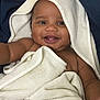 baby, smiling, towel, hooded_towel, teeth, arm, skin, blanket, happy, child, cute, infant, portrait, closeup, face, expressive, cozy, soft_texture, indoor, young