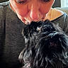 Gemma is registered to the contest to win money with this photo: person, dog, close_up, black_dog, affection, kiss, nose_ring, indoor, soft_light, fluffy_fur, face, eyes_closed, casual_clothing, love, pet, compassion, human_animal_bond, portrait, affectionate, intimate